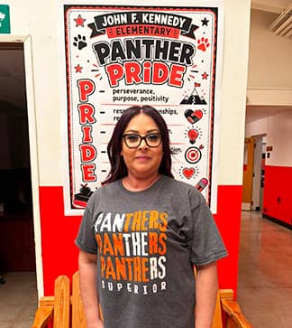 Staff member wearing community t-shirt in front of Panther's Pride poster